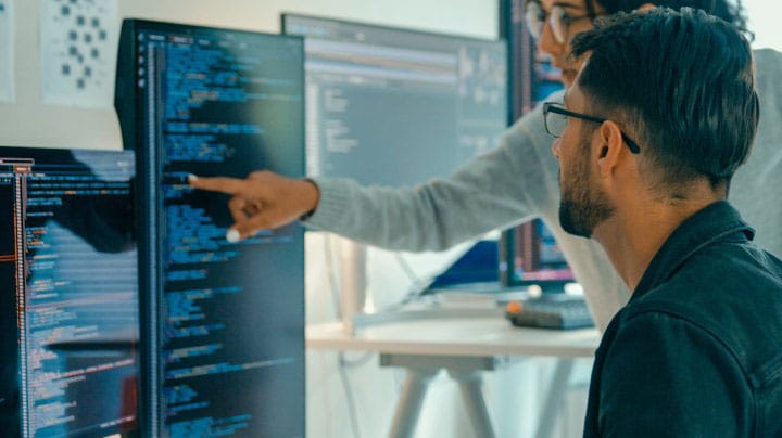People reviewing code on monitors