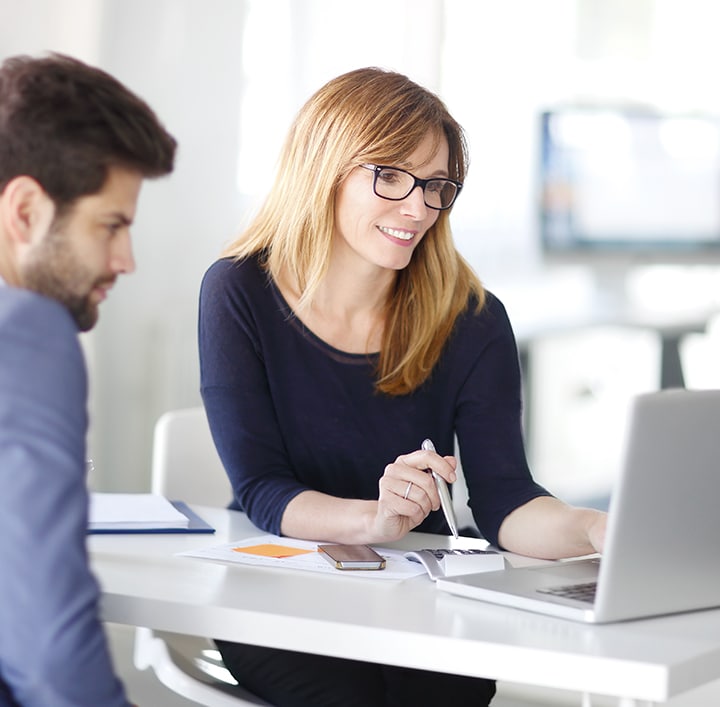  Un homme et une femme en pleine discussion et qui utilisent une calculatrice et un ordinateur portable.