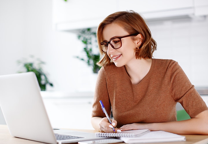 A person smiling, looking at a laptop